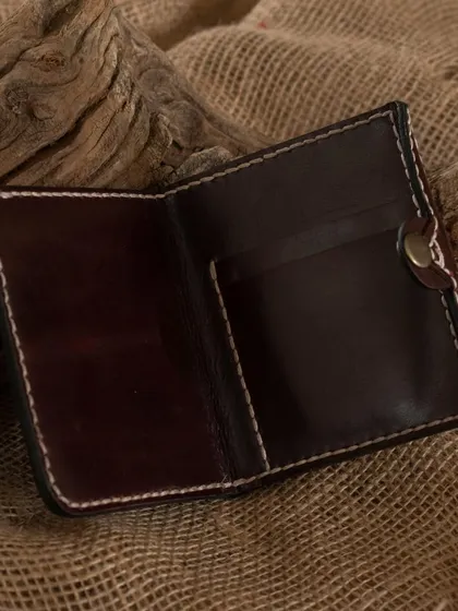 A finished leather wallet resting on a rustic background, highlighting the natural and durable quality of the materials used in our workshops.