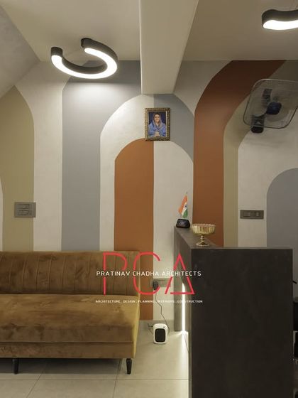 The reception and waiting area at StyleIn Homes, showing the combination of a plush sofa, 3D wall panels, and artistic paintwork.