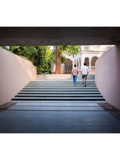 The wide, grand staircase leading down to the subterranean gallery at the Kasturbhai Lalbhai Museum. The gentle slope and generous width transform the descent into a formal procession, preparing the visitor for the exhibition below.