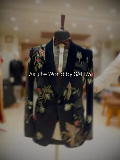 A showcase of a black velvet tuxedo jacket on a mannequin, featuring intricate floral and bird embroidery. This piece is ideal for a groom or for a high-fashion gala.