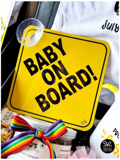 The 'Baby on Board' sign paired with a rainbow ribbon-tied jar of cookies adds a pop of color and fun to this announcement box.