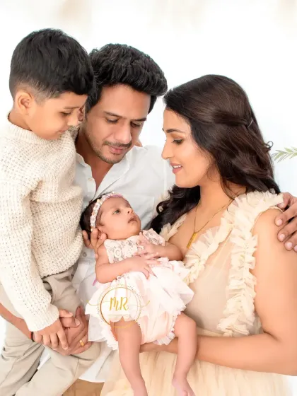 A precious moment as an older brother looks down at his new baby sister, held by their parents.