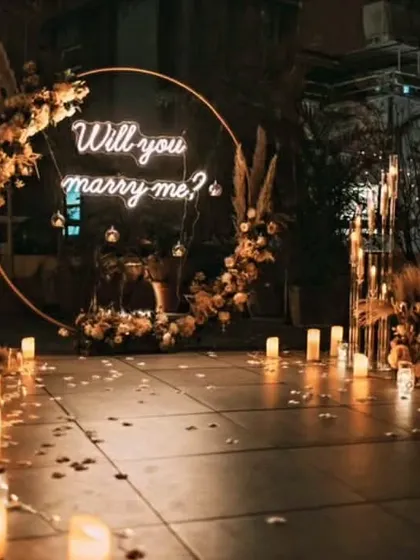 This rooftop proposal setup creates a magical atmosphere against the city lights. We used a circular arch with dried florals, a neon sign, and a pathway illuminated by dozens of candles for a breathtaking effect.
