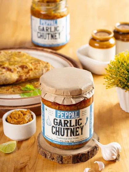 A lifestyle shot of Peppal's Garlic Chutney, styled with a plate of food. This composition shows the product as part of a complete, delicious meal.