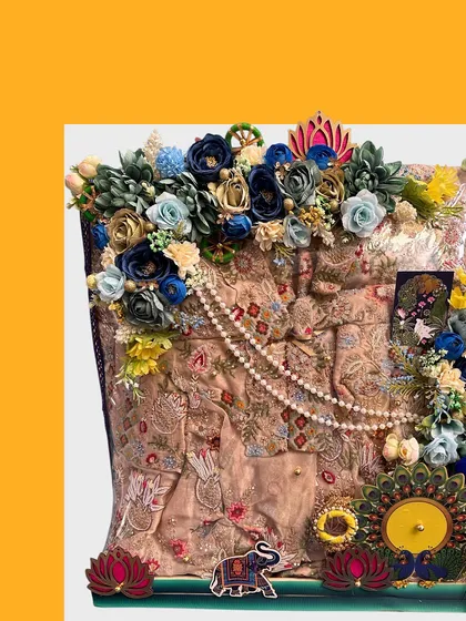 An elegant trousseau packing for a beautiful suit. The arrangement includes a pearl string, lotus and elephant motifs, and a mix of dark blue and cream flowers for a royal look.