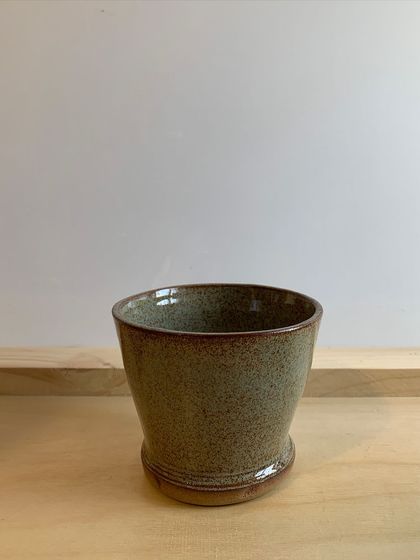 A small, speckled stoneware planter, perfect for a tiny succulent or cactus.