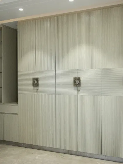 This elegant, floor-to-ceiling wardrobe integrates seamlessly into the room, featuring a built-in vanity with glass shelves for display.