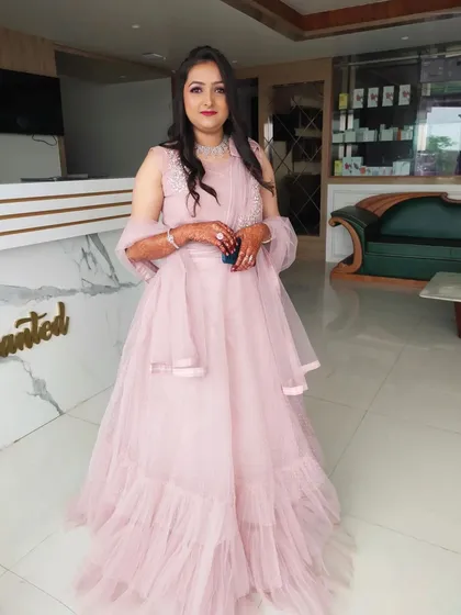 A full-length photo of a client in a beautiful pink gown for her engagement. The makeup is soft and romantic to match the fairy-tale dress.