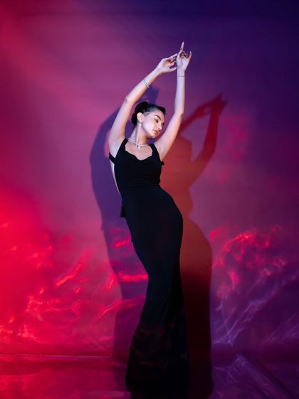 A graceful, artistic pose in the black gown, with dramatic lighting creating a beautiful, painterly effect.