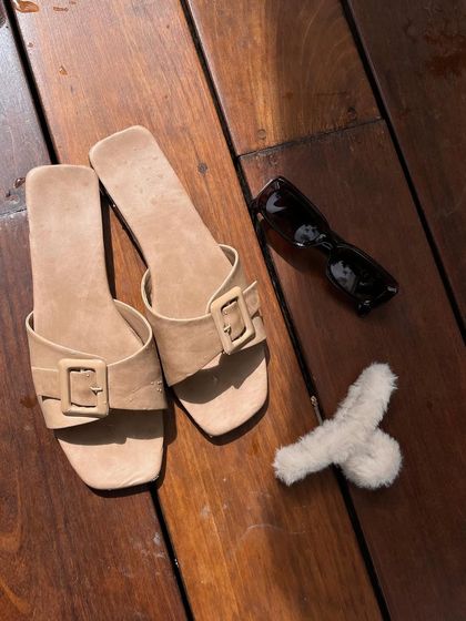 The essentials for a poolside reset: comfy slides, sunglasses, and a good book (or just a fluffy accessory).