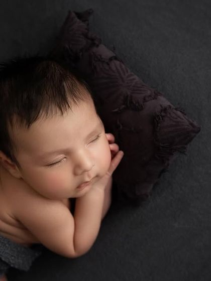 A close up shot from above, focusing on the baby's peaceful face as he rests his head on a small, textured pillow.