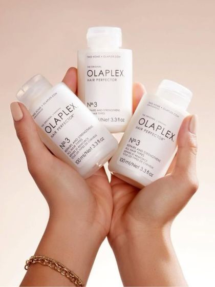 A shot of hands holding the Olaplex No. 3 Hair Perfector, a take-home treatment to keep your hair strong and healthy between salon visits.
