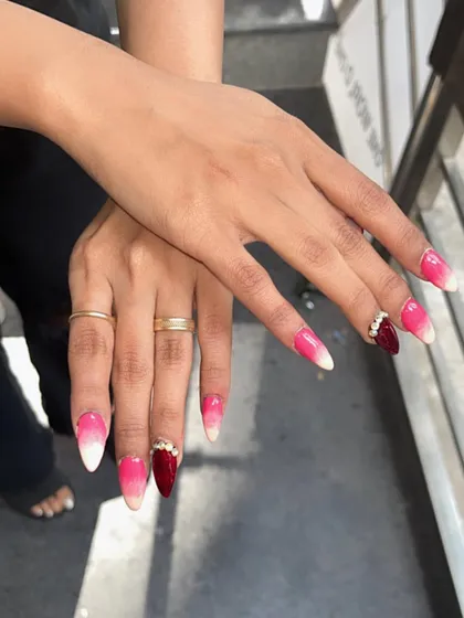 A striking ombre from white to pink to deep red on long stiletto nails, with a rhinestone cluster accent.
