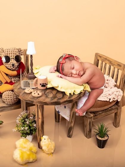 A creative and cozy setup for a sleeping newborn. The miniature furniture and teddy bear create a charming and imaginative scene.