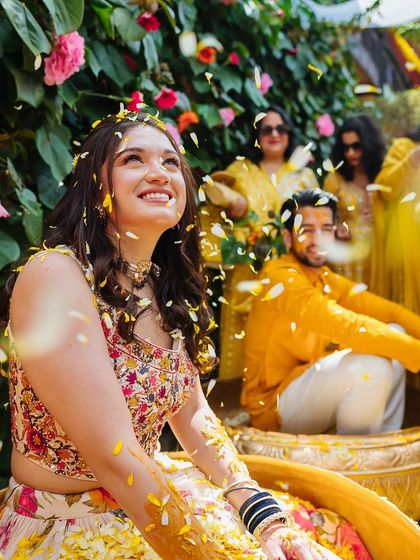A beautiful, happy portrait of the bride looking up as petals rain down on her.