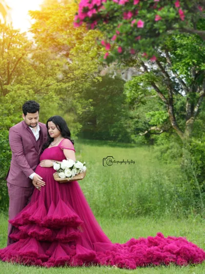 A romantic couple's portrait in a beautiful garden. The mother-to-be's wine-colored ruffled gown flows elegantly in this shot.