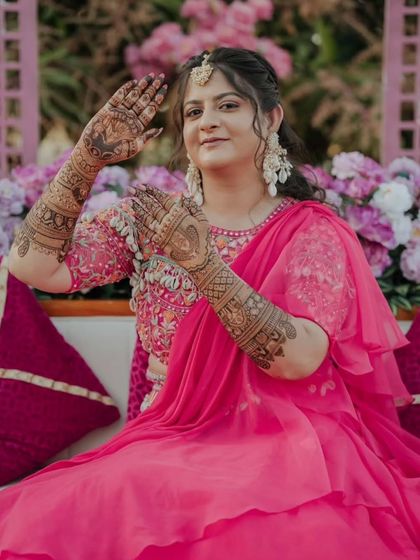A happy bride showing her palms, which feature a heart design. A sweet and romantic touch to the bridal mehandi.