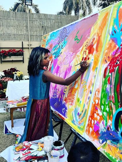 A young artist confidently adds her creative flair to the large abstract canvas at a family art party.