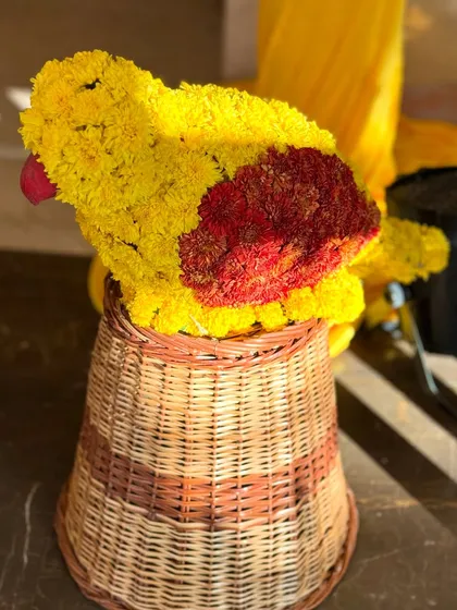 A whimsical parrot sculpture crafted entirely from yellow and red flowers. This creative floral piece sat atop a wicker basket, adding a playful and sunny element to our Haldi celebration decor.