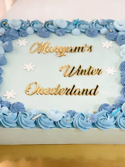 A beautiful "Winter Wonderland" sheet cake with intricate blue piping, perfect for a large party or corporate event.