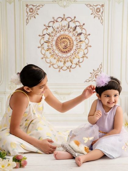 A big sister helps her little sister with her hair bow, a small, sweet gesture of sibling love captured forever.