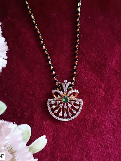A beautiful fan-shaped pendant with a central green stone adorns this modern mangalsutra. The design is unique and stylish, crafted from 92.5 silver with gold plating.