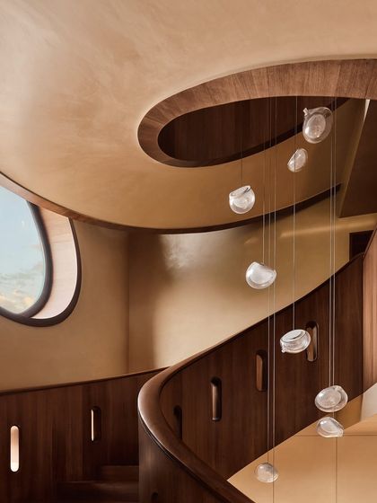 Another perspective of the cascading glass pendant lights along the spiral staircase. This angle highlights the fixture's organic, fluid form and how it interacts with the architecture of the space.