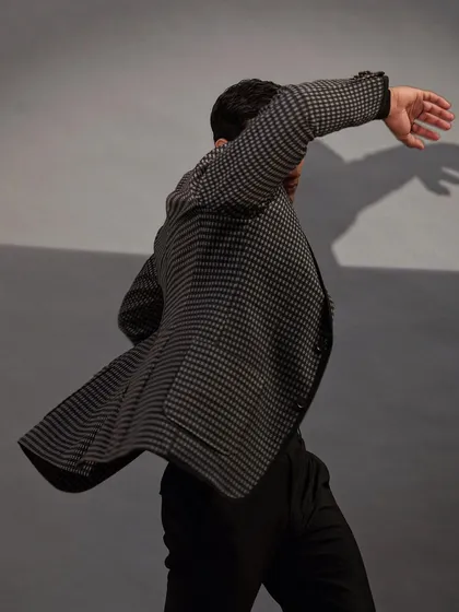 A candid moment of motion, showing how a well constructed houndstooth blazer moves with the body, proving that great style is never static.