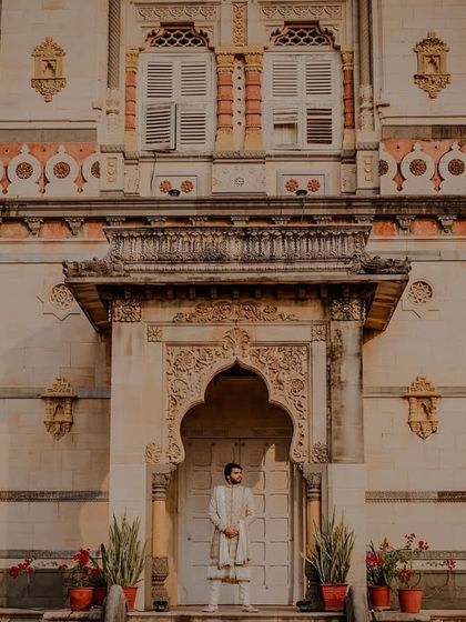 A solo portrait of the groom standing in a palace archway, looking regal.