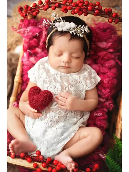 This little one is holding a heart, surrounded by festive red berries. It's a perfect setup for a baby born around a holiday or just to celebrate love.