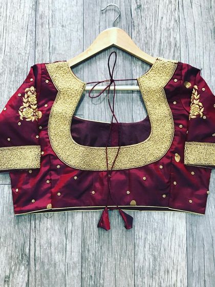 A wide U-shaped back design on a maroon blouse. The border is made with thick, solid gold threadwork for a bold and traditional look.