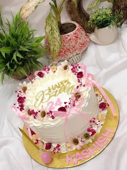 A timeless combination of a simple vintage design and delicate florals. This whipped cream cake is decorated with dried flowers and pink ribbons for a soft, romantic feel, perfect for a 24th birthday.