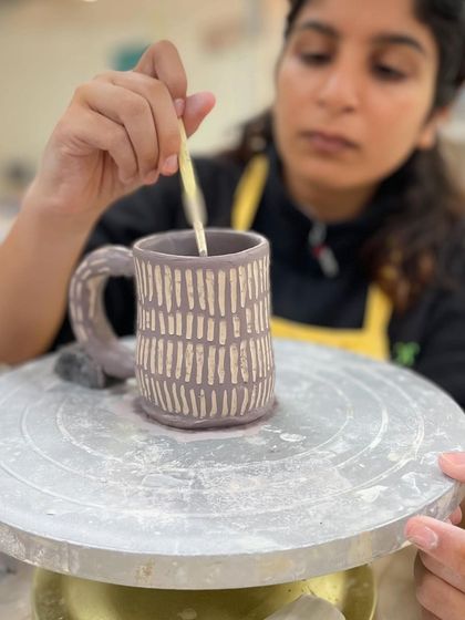 This student is using the sgraffito technique, painting a layer of color and then carving through it to reveal the clay body underneath.