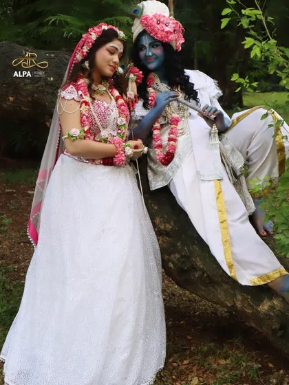 A full-length shot capturing the playful and divine interaction between Radha and Krishna, showcasing both makeovers in a natural, outdoor setting.