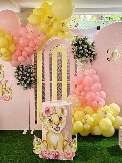 A full view of Dua's second birthday setup. The pink and yellow lion cub theme included 'TWO' letter blocks, a large balloon arch, and multiple character cutouts for a sweet and playful look.