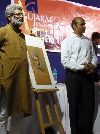 Standing beside my completed portrait of Shri Vasudevji Kamath at an event by Gujarat Kala Pratishthan. It is a moment of pride to present the artwork next to the person who inspired it.
