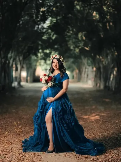 A breathtaking fairytale maternity portrait of a woman in a flowing blue gown, standing in a majestic tree-lined pathway. This shot is all about creating a sense of wonder and drama.