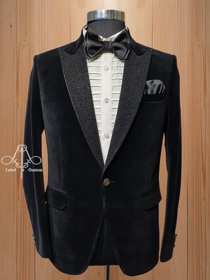 A classic black velvet tuxedo with a glittering textured lapel. This is the perfect outfit for any party, offering a timeless look with a touch of modern sparkle.