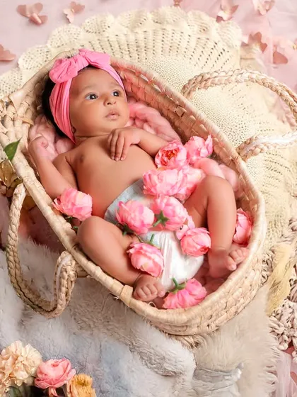 Soft, delicate, and beautiful. This newborn portrait features a baby girl nestled in a woven basket, surrounded by soft pink flowers. My studio is fully equipped with props like these to create a safe and lovely environment for your baby's first photoshoot.