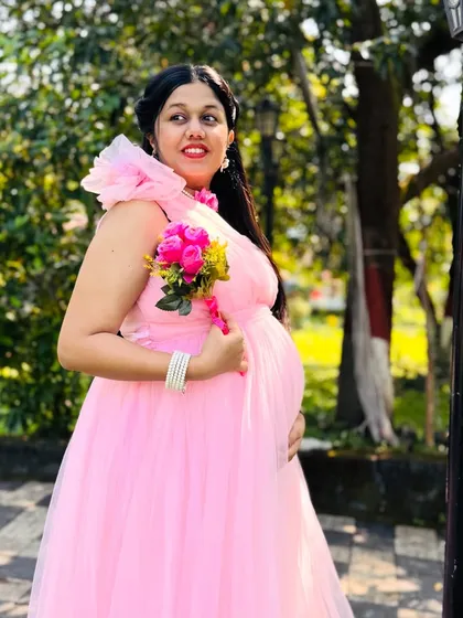 This mom-to-be is glowing in her outdoor pregnancy photoshoot. The park setting provides a simple yet beautiful backdrop for her pink gown.