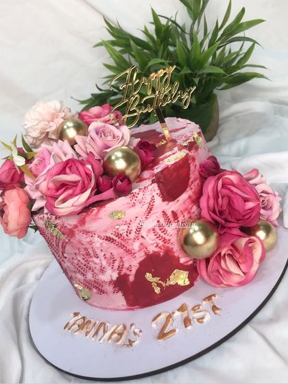 A floral cake in shades of hot pink with gold stenciling for a 21st birthday. The vibrant colors and textures create a bold and beautiful statement piece.