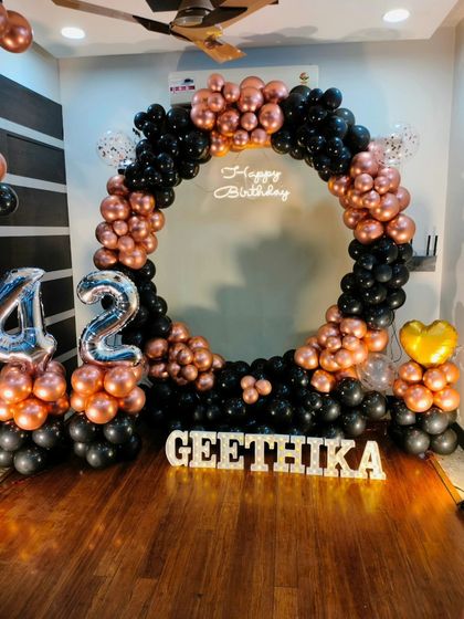 A striking black and rose gold theme for a 42nd birthday. The circular balloon arch, foil numbers, and light-up name create a personalized and sophisticated look.