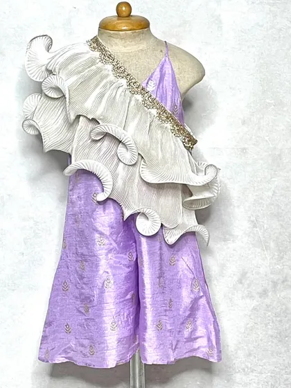 A modern take on festive wear. This lavender jumpsuit features a stunning, sculptural white frill that drapes over the shoulder, creating a high-fashion ethnic look.