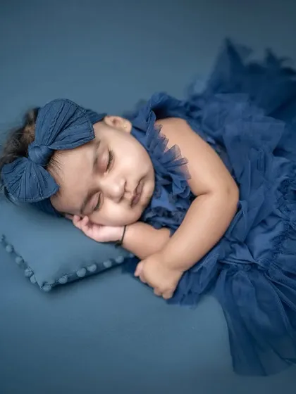 A peaceful sleeping portrait of a young baby. Dressed in a beautiful navy blue tulle dress, she looks like a tiny sleeping princess. These are perfect for capturing newborn innocence.