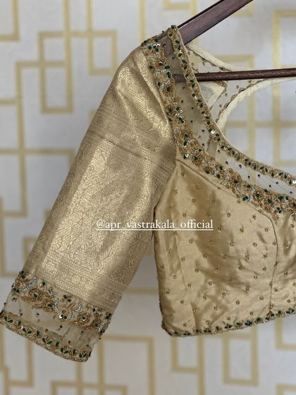 A side view of the gold blouse on a hanger.
