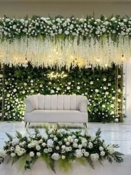 This is the kind of grand, beautiful stage I love to create for receptions and engagements. I use a full green wall, hanging white flowers, and a custom neon sign to make a stunning backdrop for your special day.