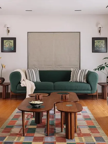 In our Cocoon House project, we curated a living space that feels both sophisticated and deeply personal. The design blends a rich emerald sofa and a patterned armchair with bespoke wooden coffee tables, all grounded by a colorful geometric rug, creating a space that is layered with character and comfort.