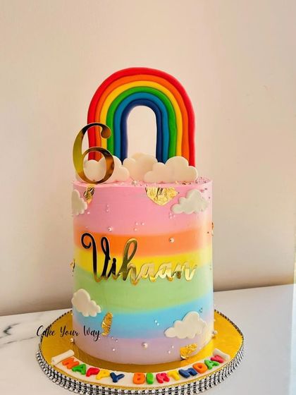 A tall rainbow cake for Vihaan's 6th birthday, with fluffy clouds and a bright, cheerful design.