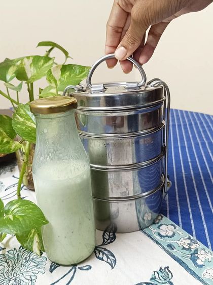 A simple shot of my tiffin carrier next to a refreshing homemade drink. It represents the complete, wholesome experience I strive to provide.