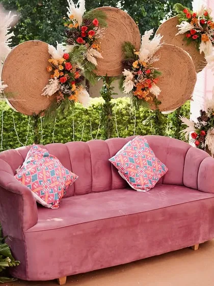 The bridal seating for a boho-themed Mehendi, designed to be a comfortable and picturesque spot for the bride. The combination of the velvet sofa and rustic backdrop is both modern and timeless.